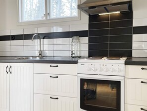 A kitchen with white cabinets, a black and white backsplash, a stainless steel sink, and a white stove. - 3 Person Holiday Home in Grimstorp (Grimstorp)