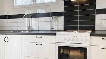 A kitchen with white cabinets, a black and white backsplash, a stainless steel sink, and a white stove.