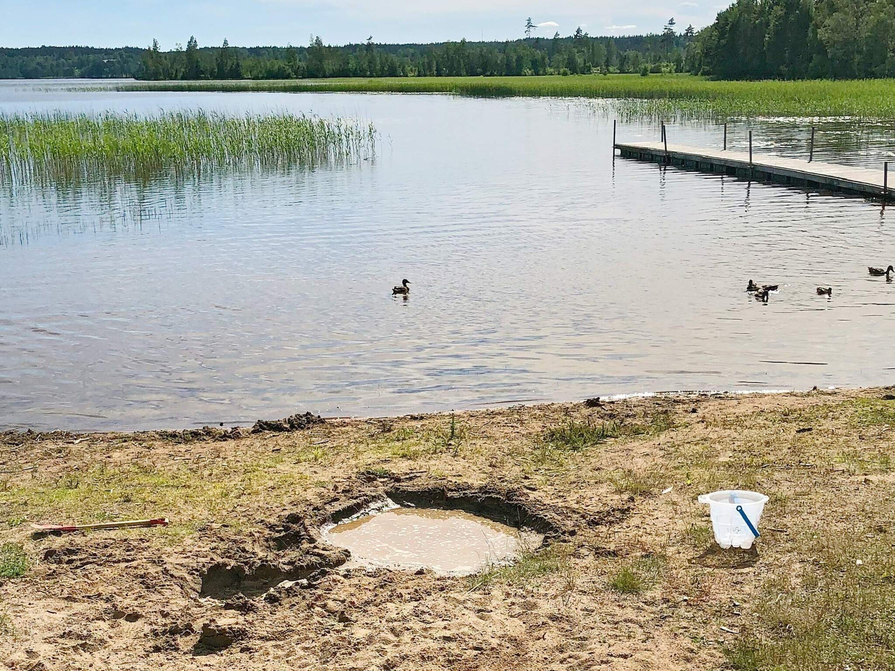 Tyyni järvi, jossa on ankkoja, laituri ja ruohikkoalue, jossa on ämpäri.
