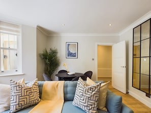 A modern living room with a sofa, a dining table, and a potted plant. - Serene Garden Retreat by Warwick Avenue (Greater London)