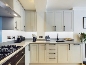 A modern kitchen with a gas stove, Bosch appliances, a sink, and a countertop with a knife block. - Serene Garden Retreat by Warwick Avenue (Greater London)