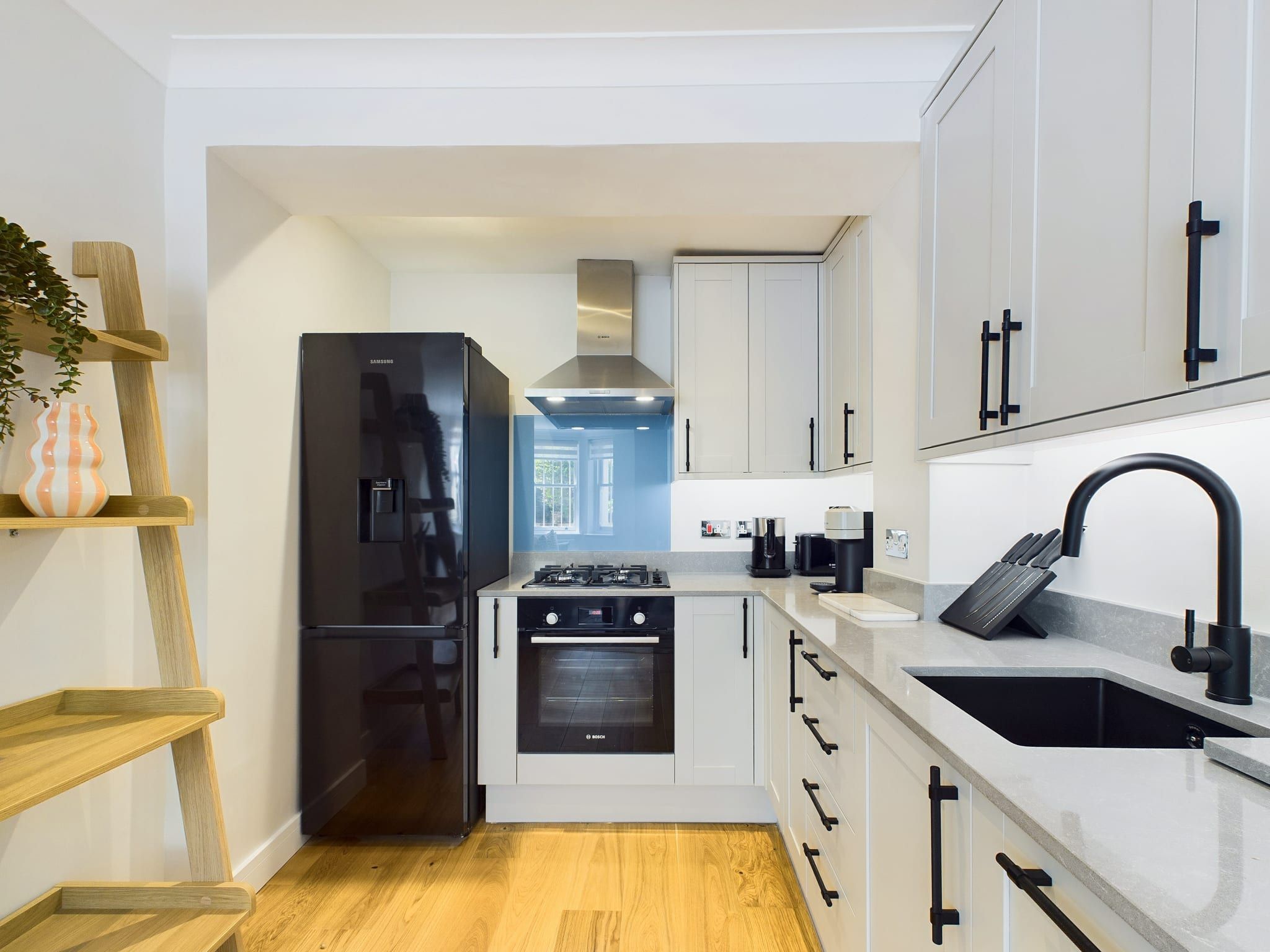 Cozinha moderna com geladeira preta, forno Bosch e pia com torneira preta.