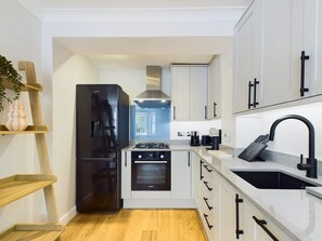A modern kitchen with a black refrigerator, Bosch oven, and a sink with a black faucet. - Serene Garden Retreat by Warwick Avenue (Greater London)