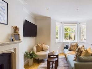 A living room with a fireplace, a television, and a sofa with patterned cushions. - Serene Garden Retreat by Warwick Avenue (Greater London)