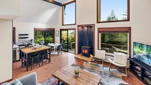 A spacious living area with a kitchen, dining table, and a fireplace. - MagicMountain~River Hideaway~View~Hot Tub~Dog~Summer Magic Retreat! EV Charge (Cazadero)