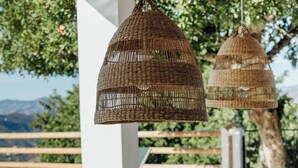 Un espace de restauration en plein air, avec des sets de table, des assiettes et des verres en osier, prêts pour un repas.