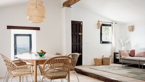 A dining area with a round table, wicker chairs, and a hanging light fixture. - Villa for up to 8 persons with fantastic mountain views & private swimming pool (Canillas De Aceituno)