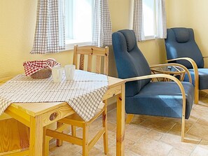 A wooden dining table with a checkered tablecloth, two blue chairs, and a wicker basket with a red and white checkered cloth. - 3 Person Holiday Home in Skivarp (Skivarp)