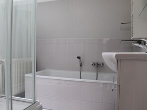 Ein modernes Badezimmer mit Duschkabine aus Glas, einer Badewanne und einem Waschbecken.