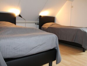 Ein Schlafzimmer mit zwei Betten, jeweils mit Kopfteil und Nachttischlampen.