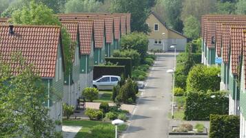 A residential street with terracotta-tiled houses, a central road, and greenery.