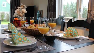 A breakfast setting with plates, glasses, and a basket of pastries.
