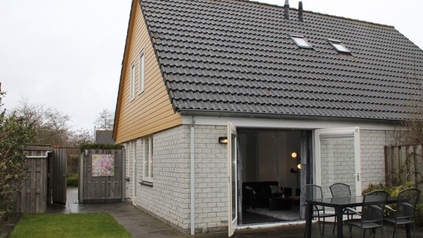 A single-story house with a tiled roof, a brick exterior, and a visible open door leading to an interior space. - Nice Holiday Home 200m. From the Beach (Wemeldinge)