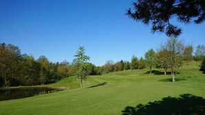 A well-maintained golf course with a pond, trees, and a clear blue sky. - 4 Person Holiday Home in Hadsund (Hadsund)