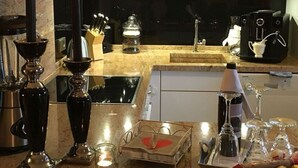 Et moderne køkken med en indbygget komfur, kaffemaskine og diverse køkkenredskaber.