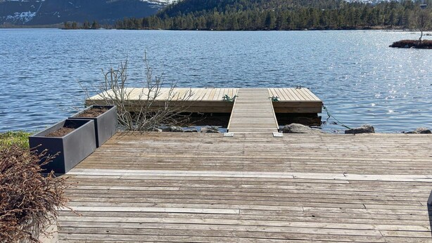 A wooden dock extending into a lake with snow-capped mountains in the background. - 8 Person Holiday Home in Hovden-by Traum (Bykle)