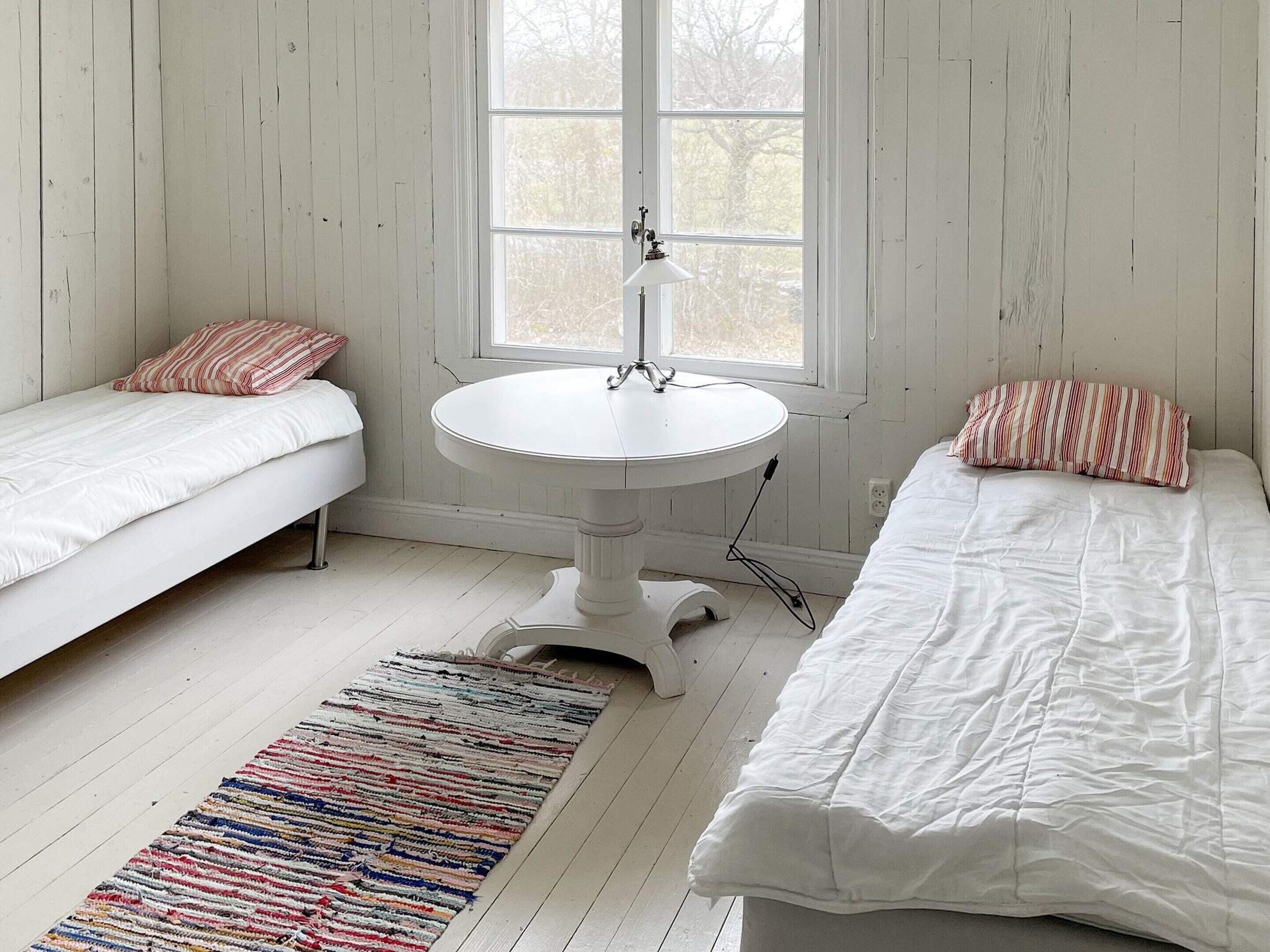 A room with two beds, a round table, and a window.