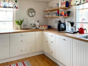 A kitchen with white cabinets, a wooden countertop, a coffee maker, and a red kettle. - 8 Person Holiday Home in Hogsby (Högsby)