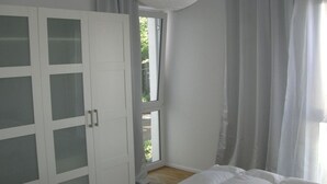 Ein Schlafzimmer mit einem Bett, einem Schrank mit Glastüren und einem Fenster mit Vorhängen.