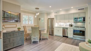 A modern kitchen with a dining area, featuring a refrigerator, microwave, oven, and a dining table with chairs. - Kiawah Exclusives | 4270 Mariners Watch (Johns Island)