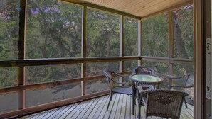 A covered outdoor area with a table and chairs, large windows, and a wooden ceiling. - Kiawah Exclusives | 4270 Mariners Watch (Johns Island)