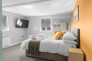Una habitación de hotel con cama, televisor en la pared, ventana con vistas y radiador.