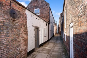 Un estrecho callejón con edificios de ladrillo, una puerta blanca y una ventana.