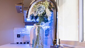 Una cocina con un lavamanos de acero inoxidable, un florero con flores y un grifo moderno.