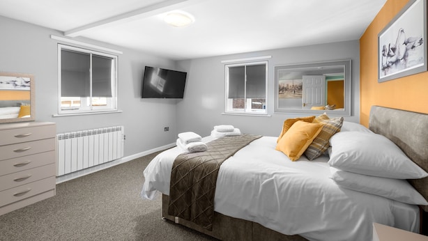 Una habitación de hotel con cama, cómoda, televisor y ventana.