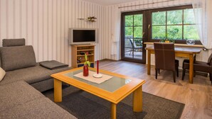 En stue med sofa, sofabord, fjernsyn og et spiseområde med bord og stole.