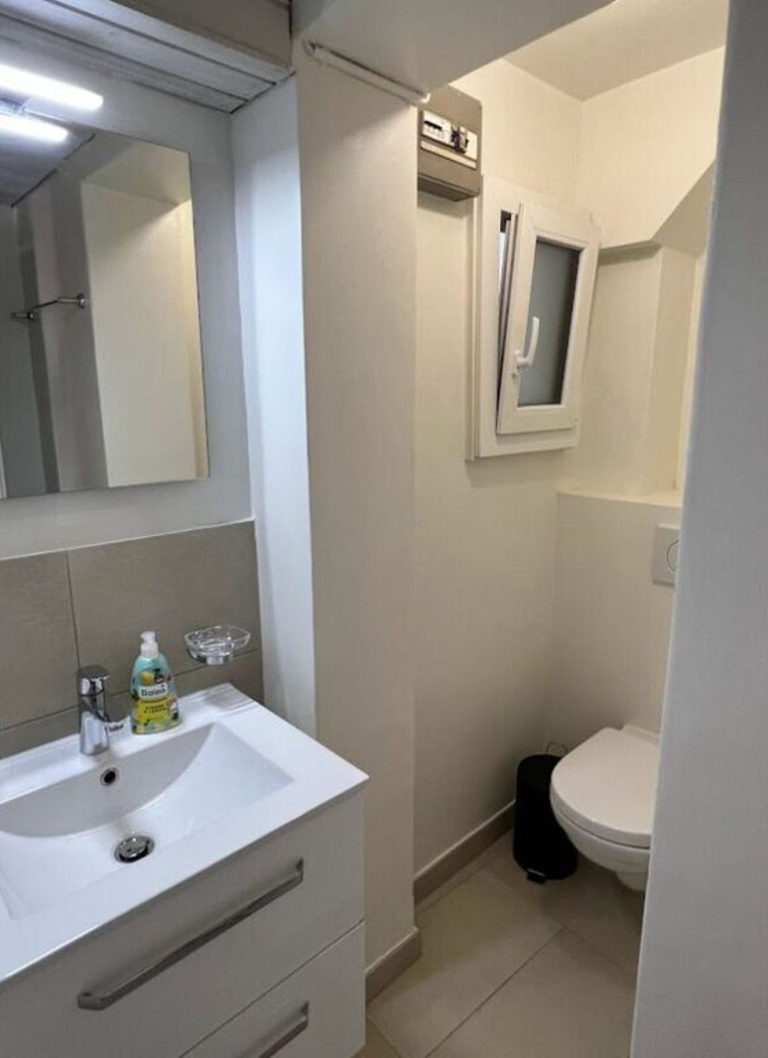 Un bagno piccolo con un lavandino bianco, uno specchio, un water e un armadietto.