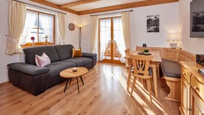 A spacious living area with a sofa, a small round table, wooden flooring, and a dining set. - "karwendel" Modern Retreat (Kruen)