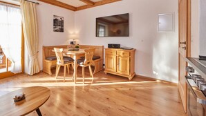 A cozy dining area with a wooden table and chairs, a wooden cabinet, and a television mounted on the wall. - "karwendel" Modern Retreat (Kruen)