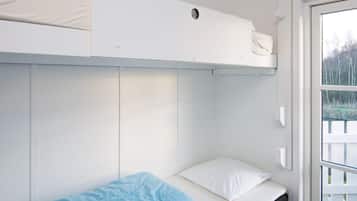 A bunk bed room with a white mattress on the lower bunk and a single bed with a blue blanket on the upper bunk.