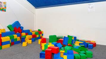 A room with scattered colorful building blocks on the floor and a blue ceiling.