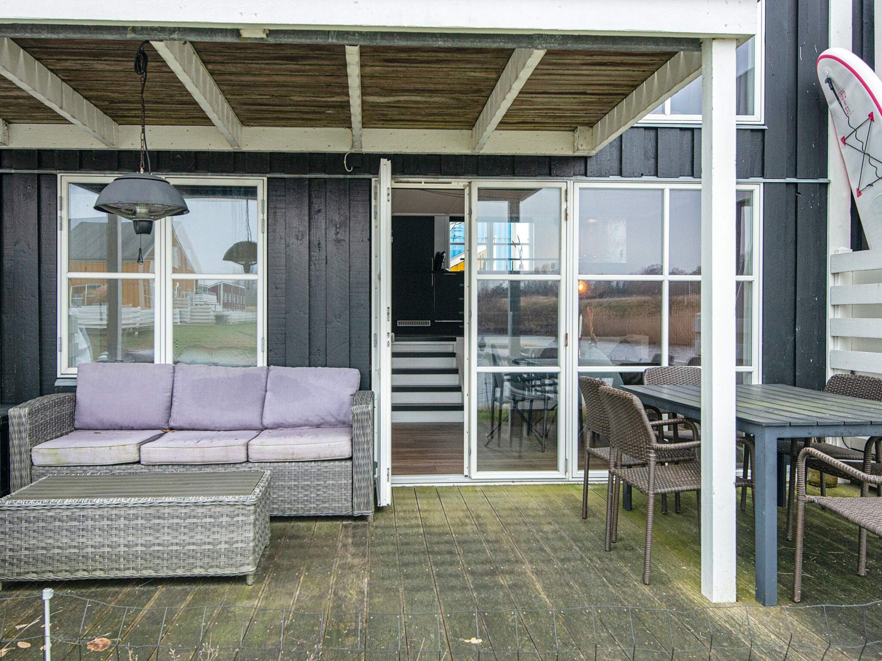 Une terrasse extérieure avec un canapé en osier, une table et des chaises.