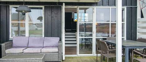 Une terrasse extérieure avec un canapé en osier, une table et des chaises.
