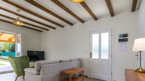 Ein Zimmer mit einer Couch, einem Fernseher, einem Holztisch, einer Lampe und einer Tür mit Notausgangsschildern.