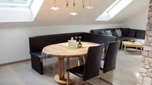 A modern living room with a round wooden table, black leather chairs, a black sofa, and a stone accent wall.