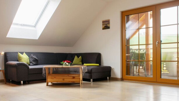 A modern living room with a dark grey sofa, a wooden coffee table, and a skylight above.