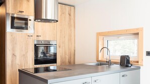 Una cucina moderna con mobili in legno, elettrodomestici in acciaio inossidabile, una finestra e un forno a incasso.