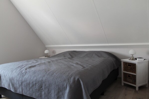 Un dormitorio con cama, mesita de noche y lámpara.