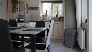 A compact kitchen with a dining area, a built-in oven, a coffee maker, and a trash bin. - Nice Holiday Home With Garden Near Beach (Wemeldinge)