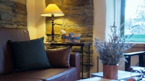 Una sala de estar acogedora con un sofá de cuero, una mesa con una lámpara y vistas al exterior a través de una ventana.