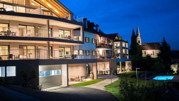 Een meerhoog hotel met buiten zitplaatsen en een zwembad.