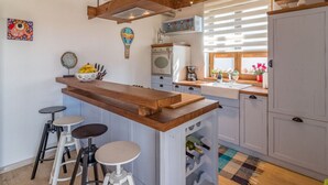 A kitchen with a wooden island, bar stools, a wine rack, and a window with plants. - Villa Malena Comfortable Holiday Residence (Svetvincenat)