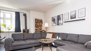 Un salon moderne avec un canapé d’angle gris, une table basse ronde et une cheminée.