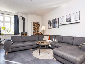 A modern living room with a grey sectional sofa, a round coffee table, and a fireplace. - 5 Star Holiday Home in Grindsted (Grindsted)