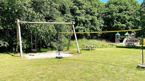 A grassy outdoor area with a swing set, picnic table, and tire swing. - 5 Star Holiday Home in Grindsted (Grindsted)