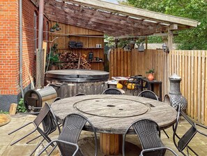 An outdoor patio with a round wooden table and chairs, a barbecue grill, and a wooden fence. - 5 Star Holiday Home in Grindsted (Grindsted)